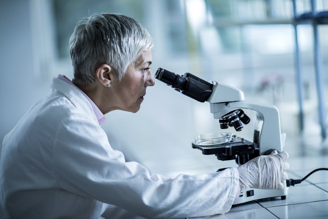 Mature scientist looking through a microscope in the laboratory.